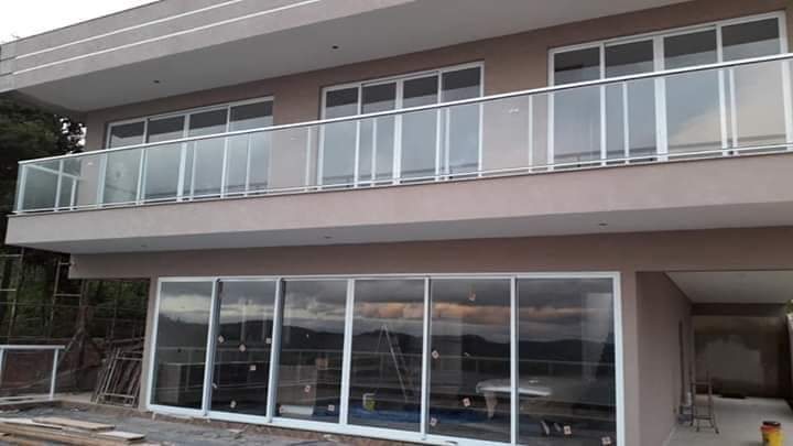 Fachada de sobrado com pintura em tom rosé e sacada de vidro